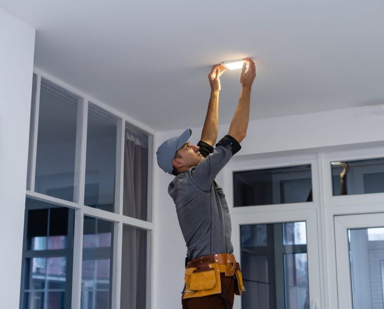An electrician is installing spotlights on the ceiling relamping_dowlight_reglette